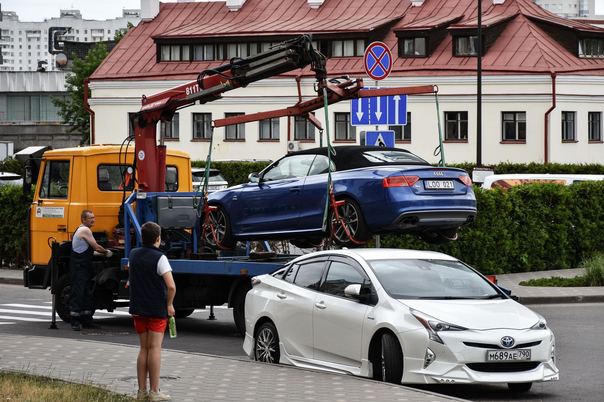 Towing a blue Audi convertible in a bustling city street.